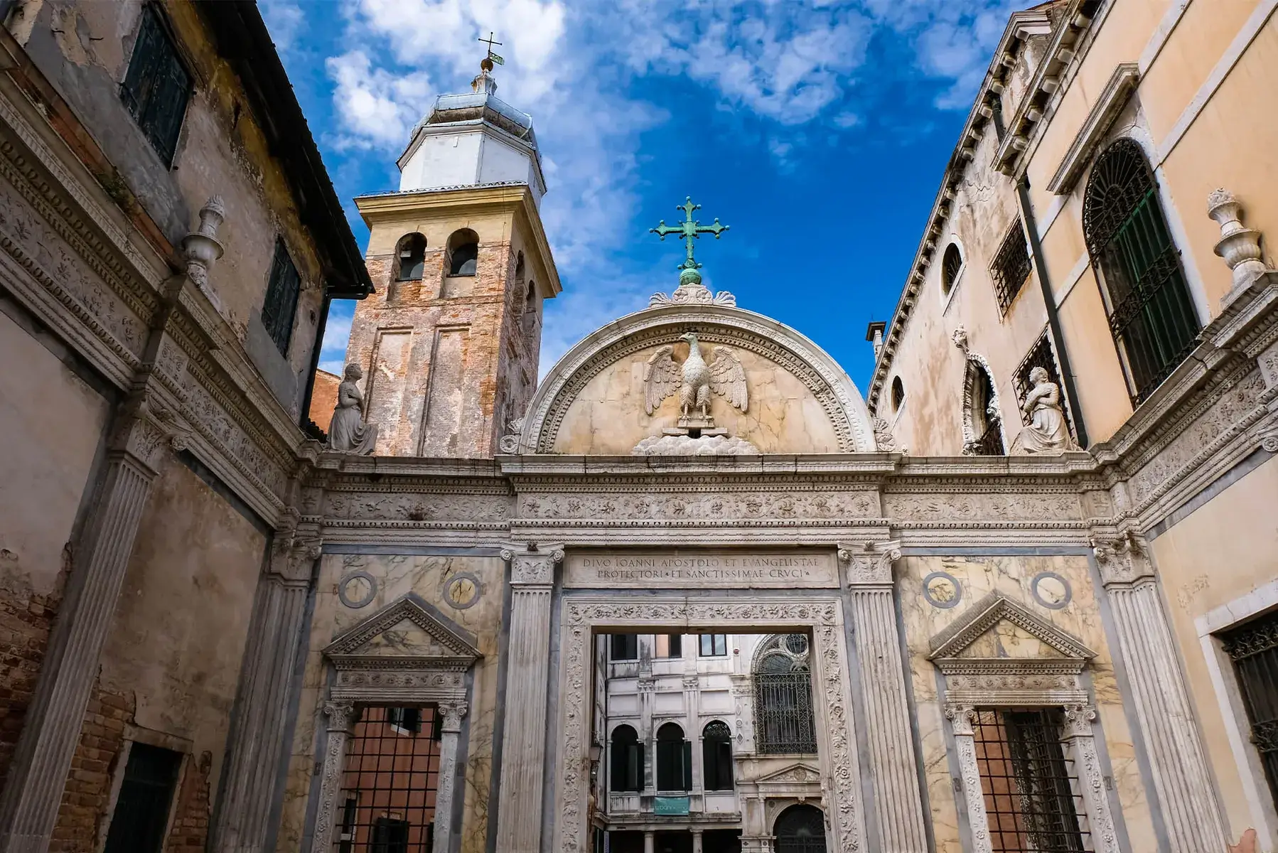 Facciata storica decorata con intagli e torre dell'orologio sullo sfondo del cielo azzurro.