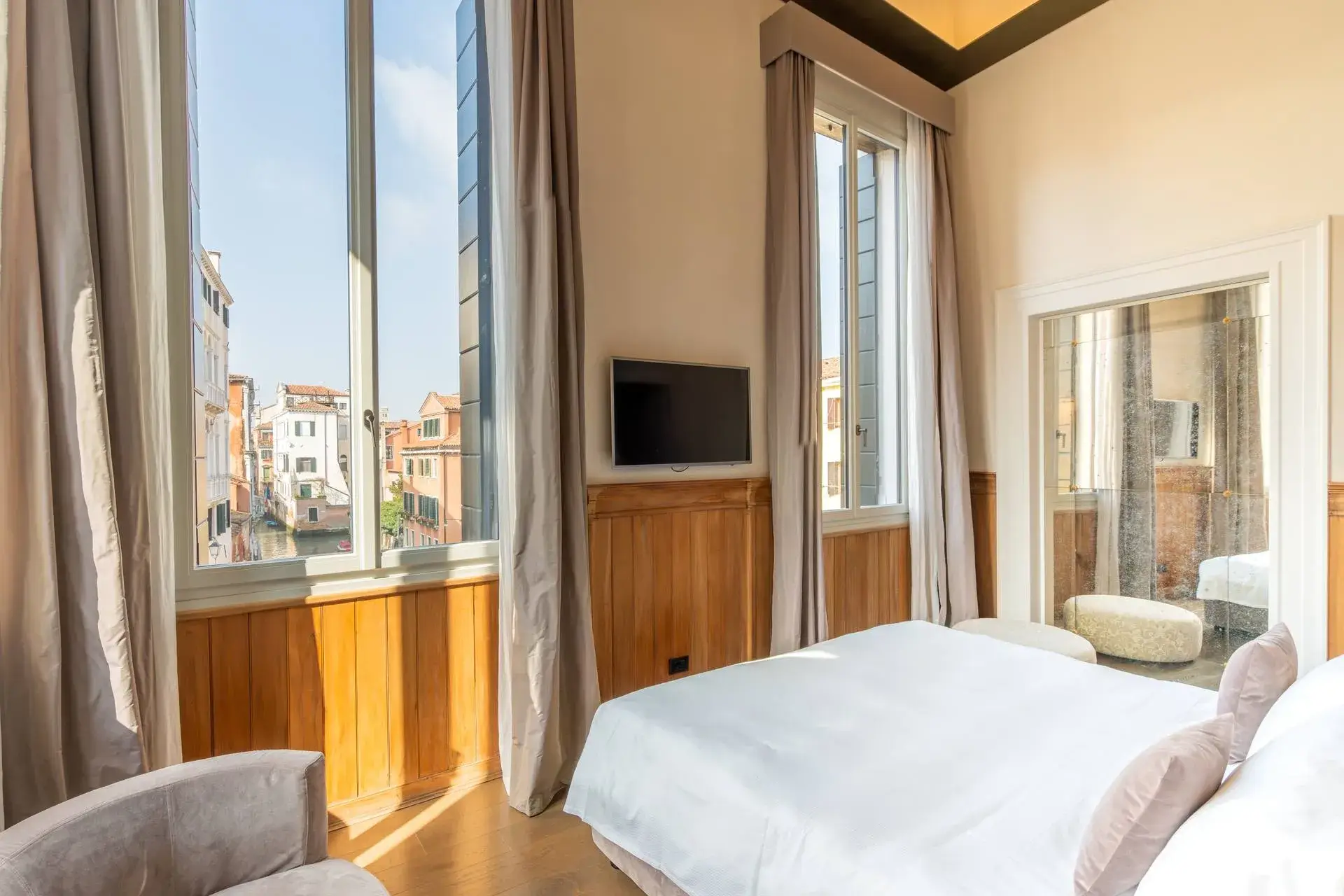 Camera d'albergo: grandi finestre, letto, TV a parete, vista sulla città.