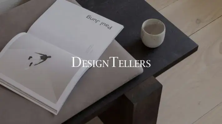 Libro aperto, tazza sul tavolo e sovrapposizione "Design Tellers".