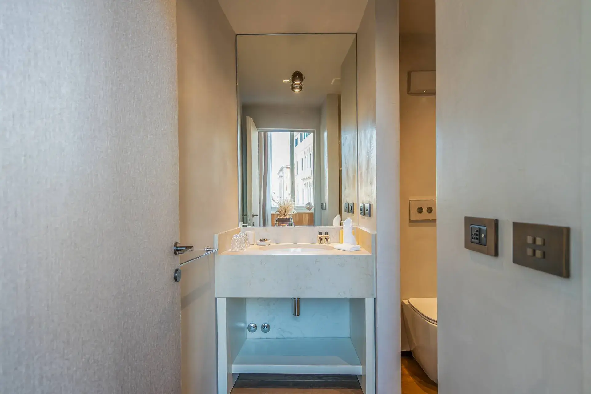 Sleek sink, large mirror, minimalist decor in a modern bathroom, seen from the door.