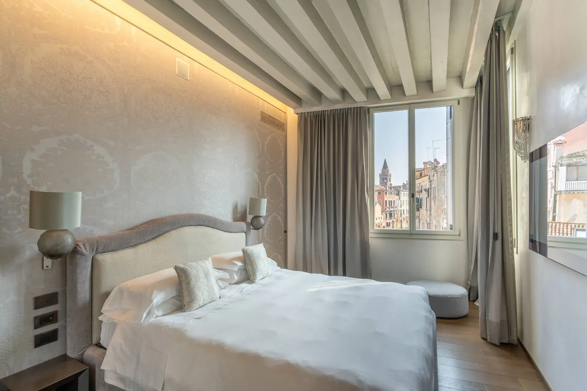 A cozy bedroom with a large bed, stylish lighting and a view of the city.