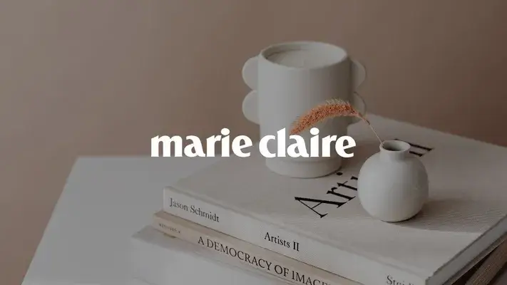 Arredamento minimalista: vasi bianchi, libri impilati sul tavolo, testo sovrapposto "marie claire".