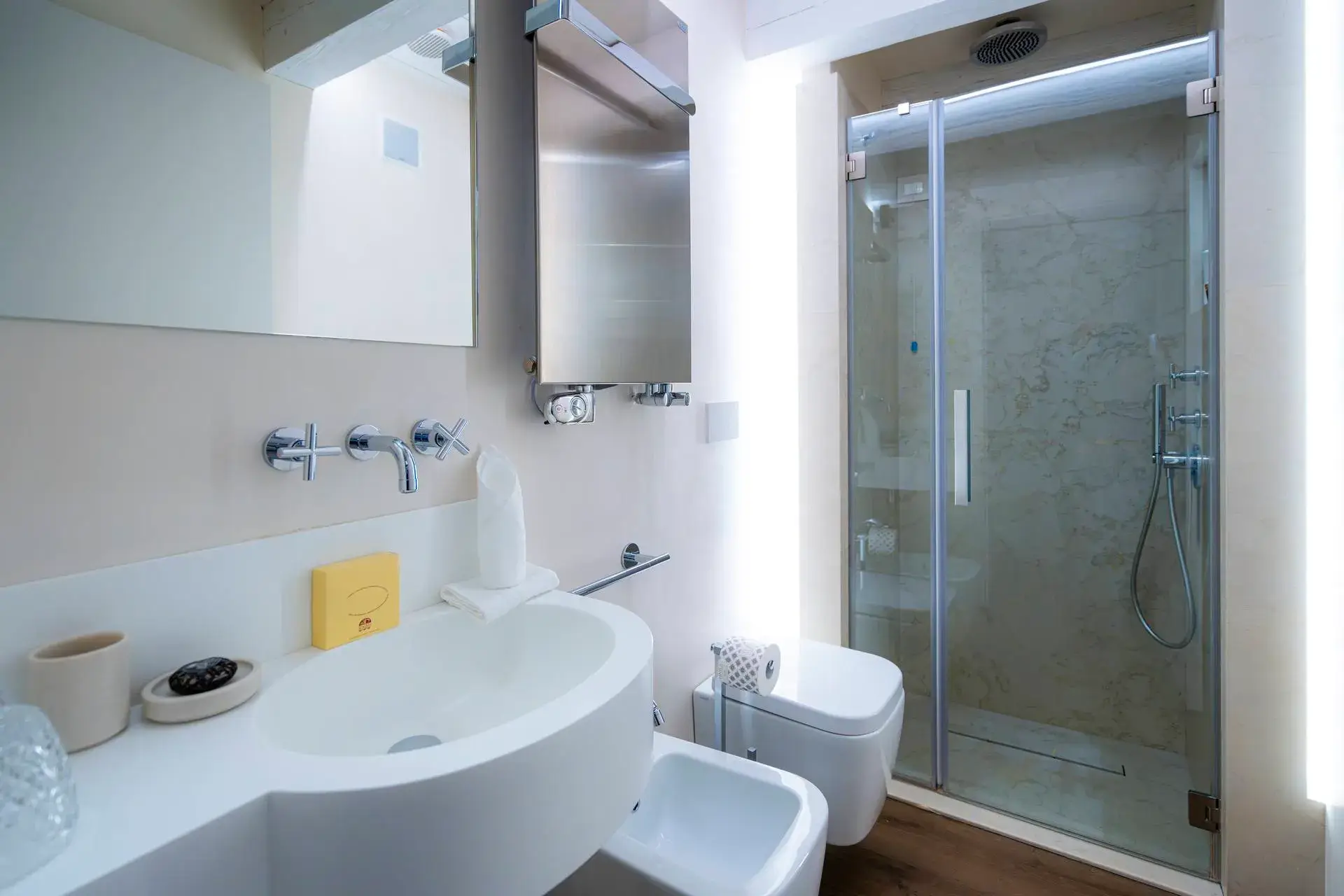 Bagno moderno: doccia in vetro, lavandino bianco, portasciugamani, luci soffuse, arredamento minimalista.