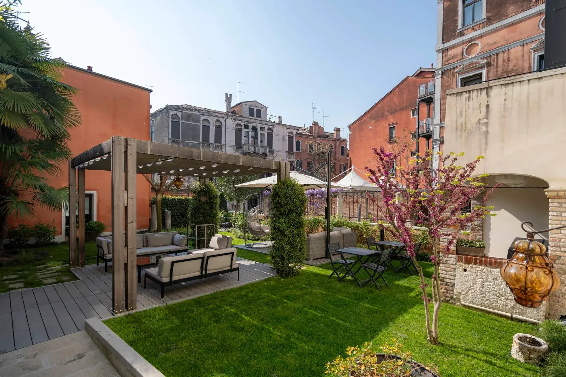 Un giardino vivace con pergolato e posti a sedere, circondato da colorati Palazzo Morosini degli Spezieri.