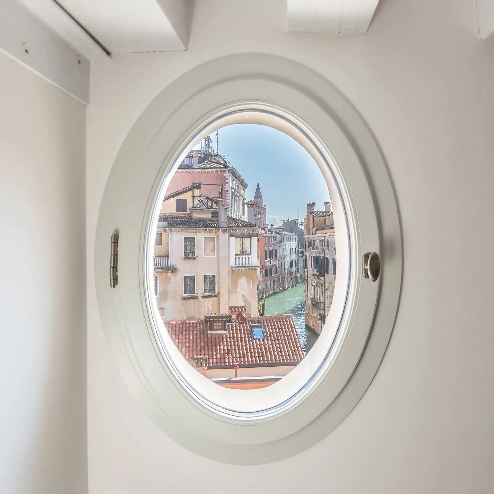 View of vibrant Venetian buildings and a canal through a round window.