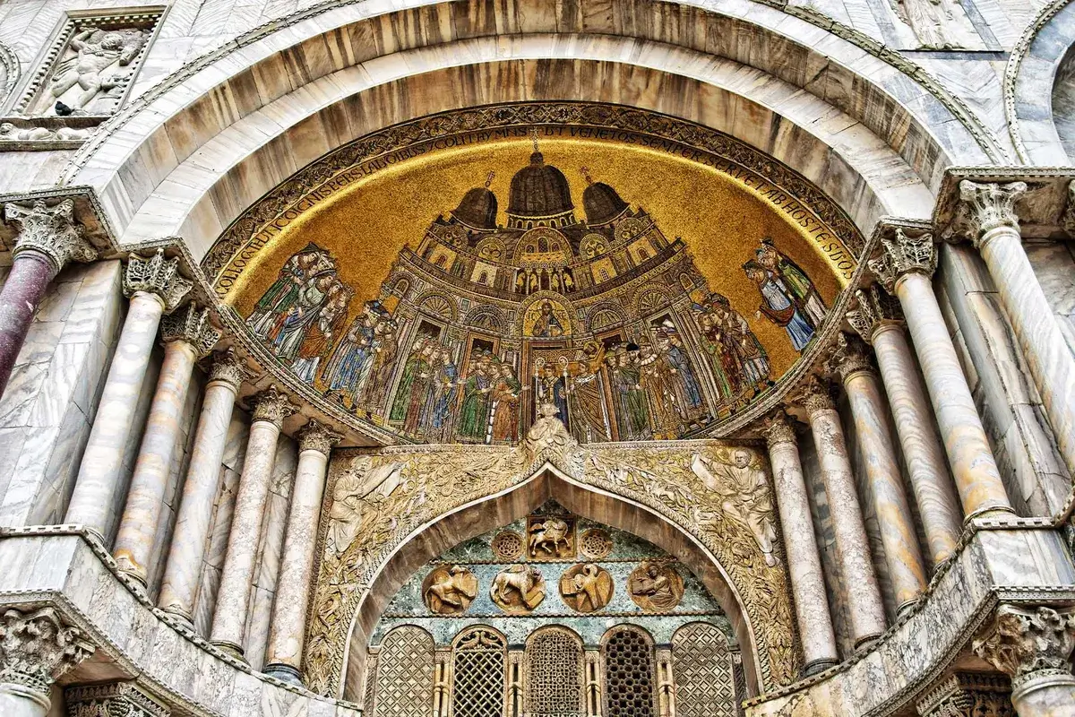 Facciata decorata della chiesa con intagli, mosaici dorati, colonne di marmo e archi decorativi.