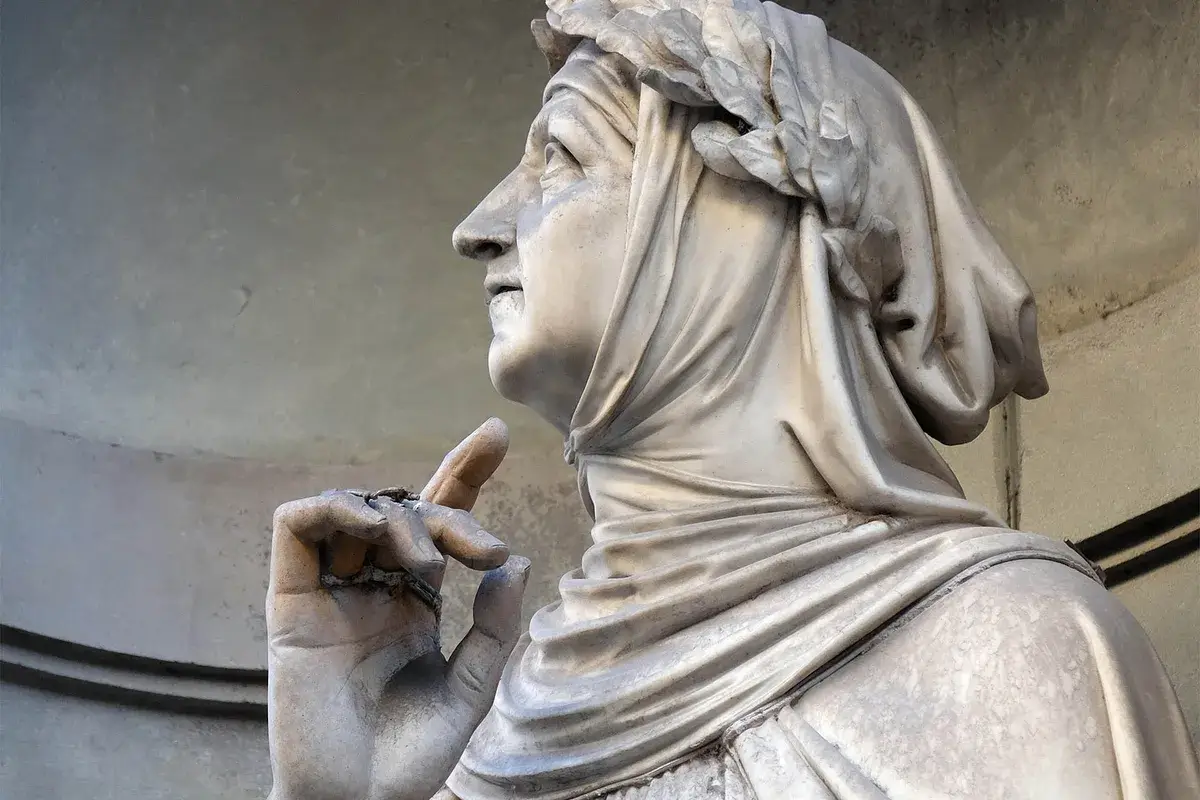 Statua in pietra raffigurante una persona con un foulard in testa, una corona d'alloro e una mano alzata con l'indice rivolto verso l'alto.