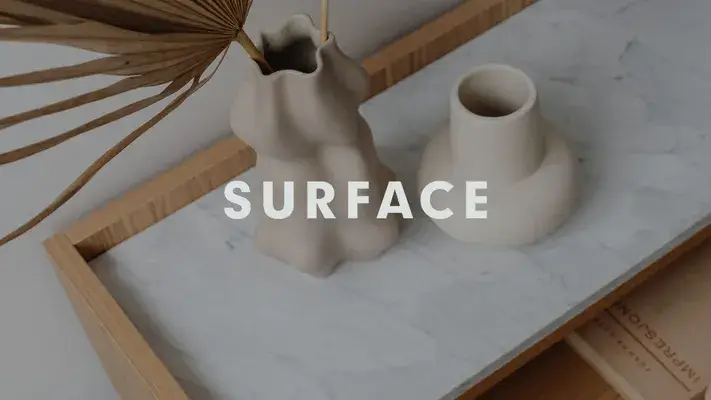 Due vasi su un piano di marmo con la scritta "SURFACE" sovrapposta.