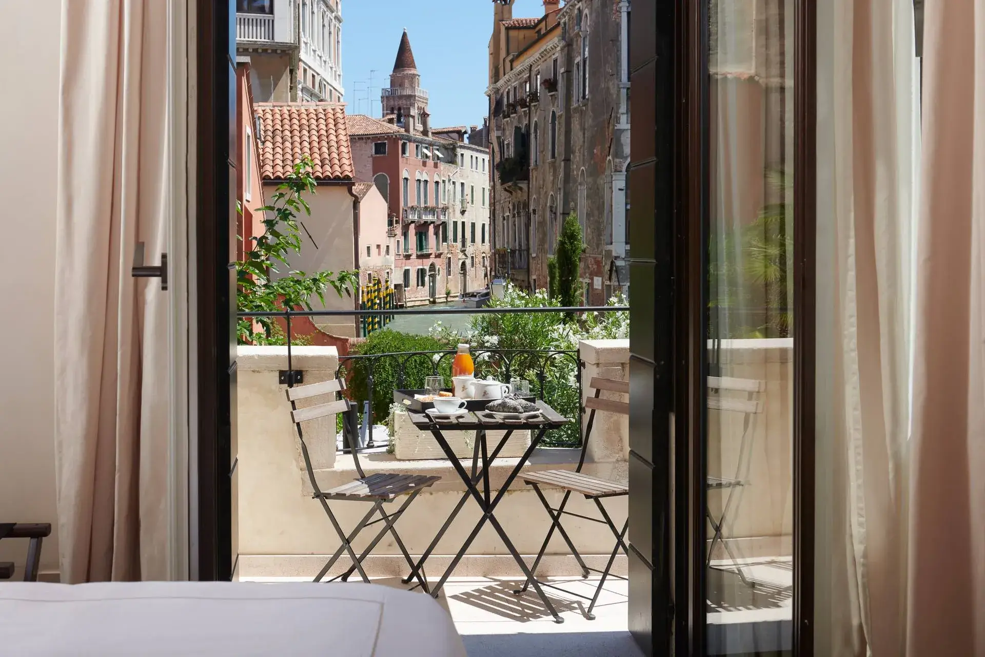 Le porte-finestre del balcone si aprono su una vista sul canale, con tavolo e sedie per la colazione.